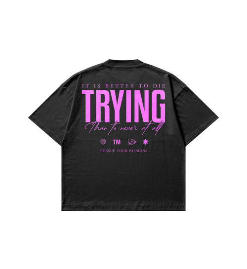 A black short-sleeve t-shirt shown from the back, featuring a large graphic print in pink text that reads 'IT IS BETTER TO DIE TRYING than to never at all.' with Club Cosmos icons below.