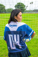 Woman wearing a blue and white sports jersey with 'Club Cosmos' branding on a soccer field.