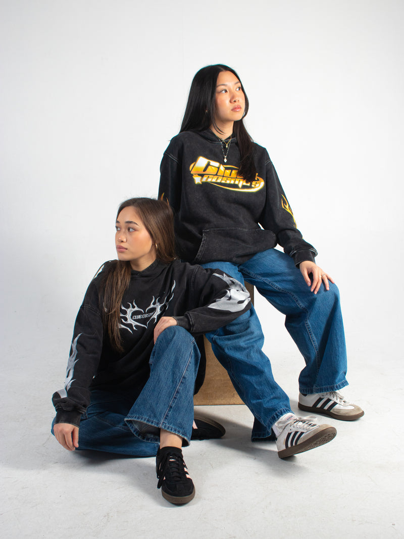 Two models wearing black Club Cosmo's hoodies with different logos sitting on a white background.