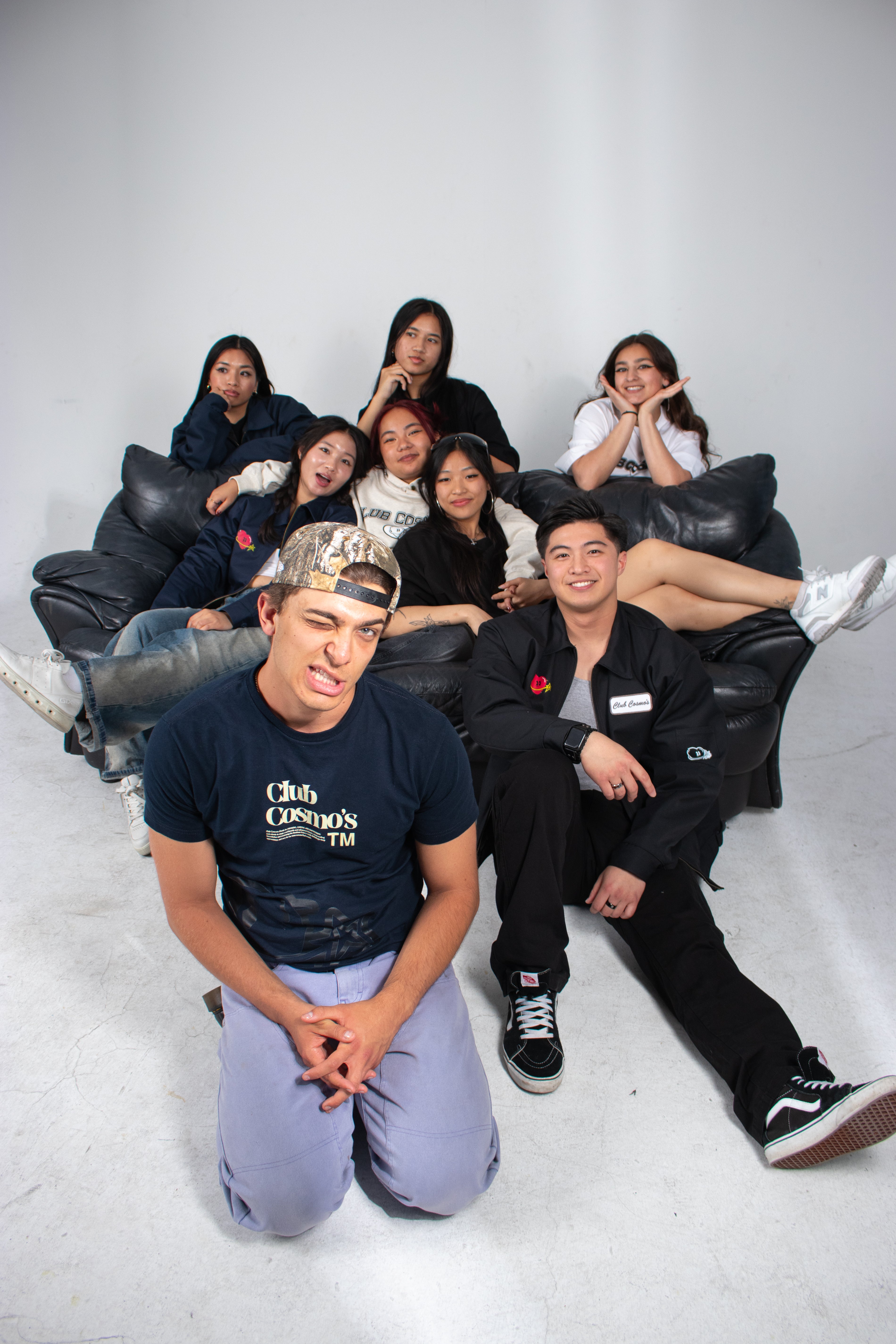 Group of models wearing Club Cosmo's merchandise posing on a couch against a white background.