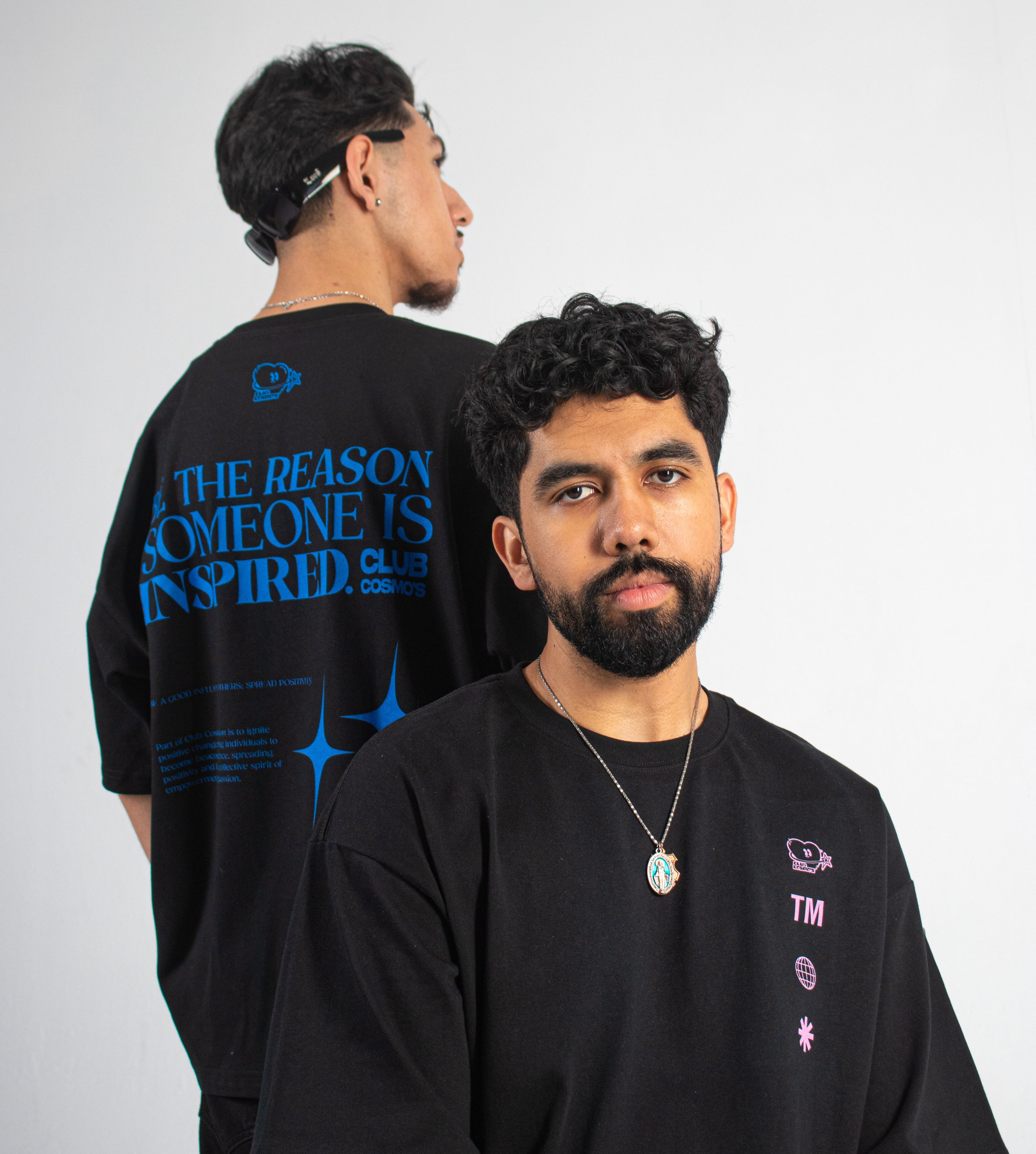 Two models wearing black Club Cosmo's t-shirts with text and graphics on a plain white background.
