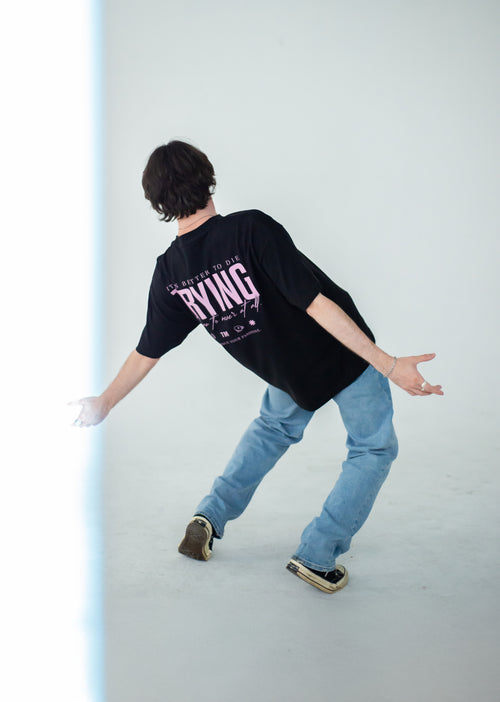 Model wearing a black Club Cosmo's t-shirt with pink text and light blue jeans on a white background.