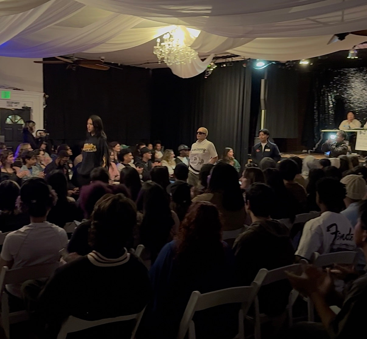 Audience in a room with a runway and Club Cosmo's models on it.