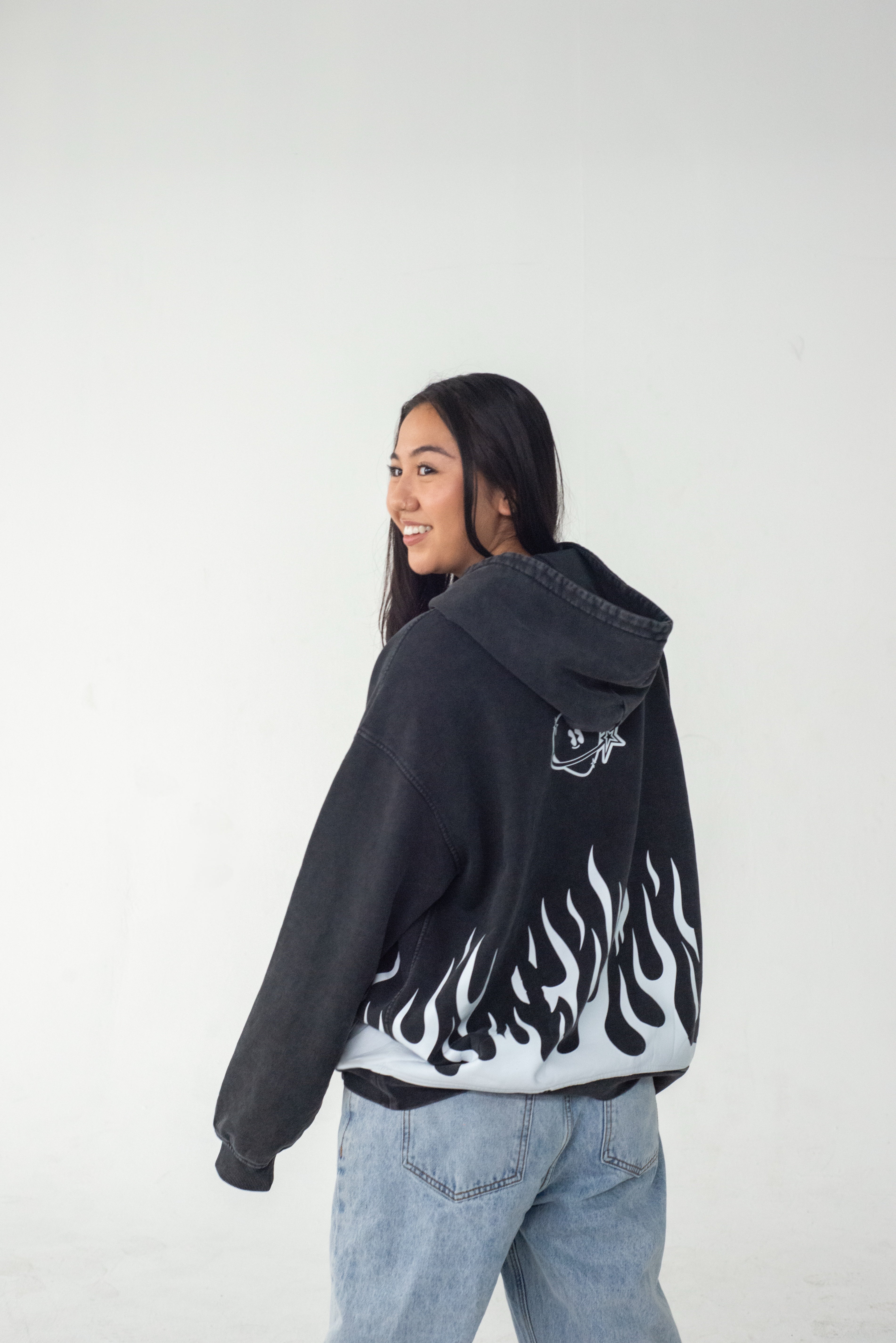 Model wearing a black hoodie with flame design and Club Cosmo's logo on the back against a white background.