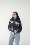 Model wearing a black hoodie with white text 'Club Cosmo's' and flames, standing against a white background.