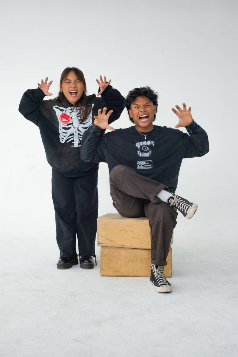 Two people posing energetically wearing Halloween themed Club Cosmo's merchandise on a white background.