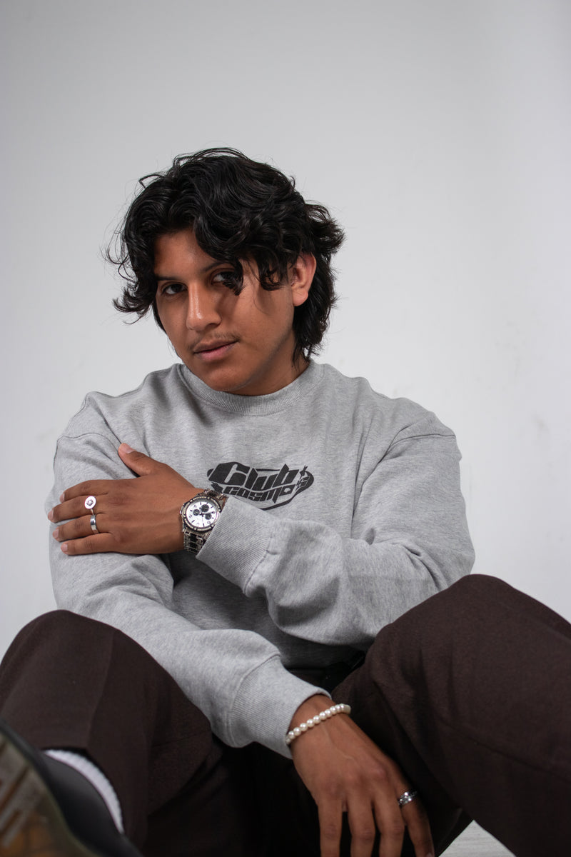 Model wearing a grey Club Cosmo's sweatshirt with the alternative logo, sitting against a plain white background.