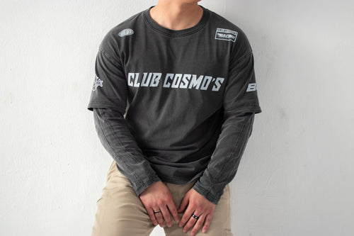 Model wearing a black long-sleeve shirt with 'CLUB COSMO'S' text and graphics on a white background.