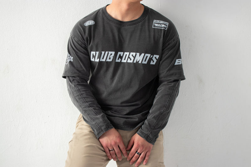 Model wearing a black long-sleeve shirt with 'CLUB COSMO'S' text and graphics on a white background.