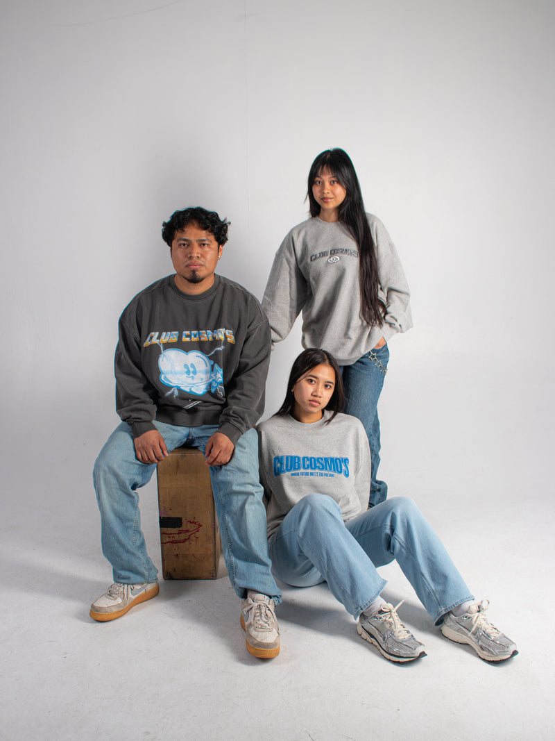 Three people wearing grey Club Cosmo's sweatshirts with a text logo and graphics on a white background.
