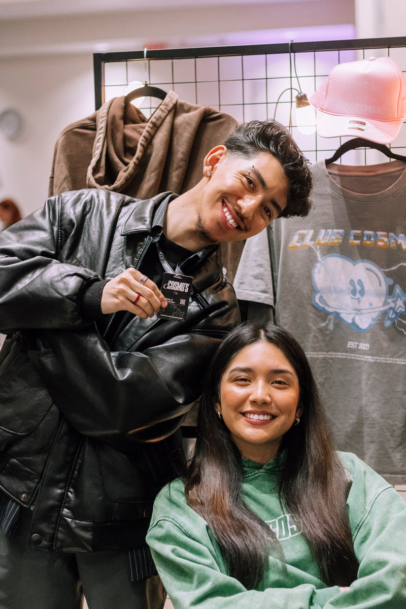 Two Club Cosmo's collectives posing together with clothing items in the background.