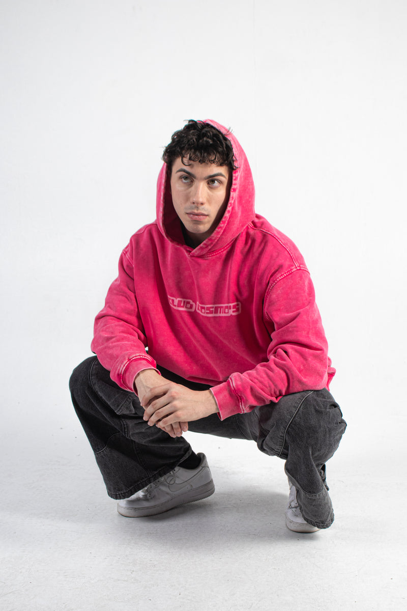 Model wearing a pink Club Cosmo's hoodie with text on a white background.