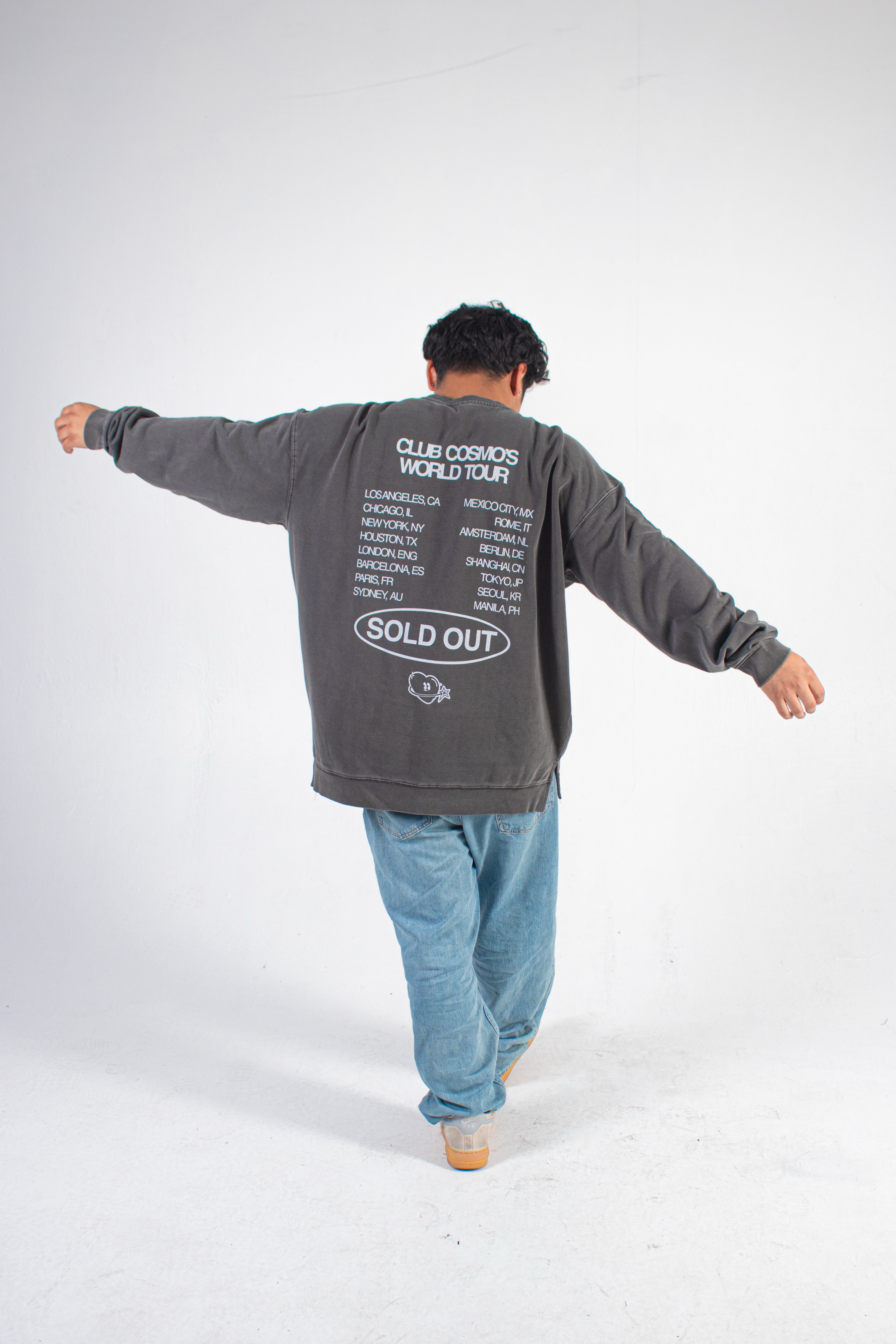 Person wearing a gray Club Cosmo's sweatshirt with text on the back, standing against a white background.