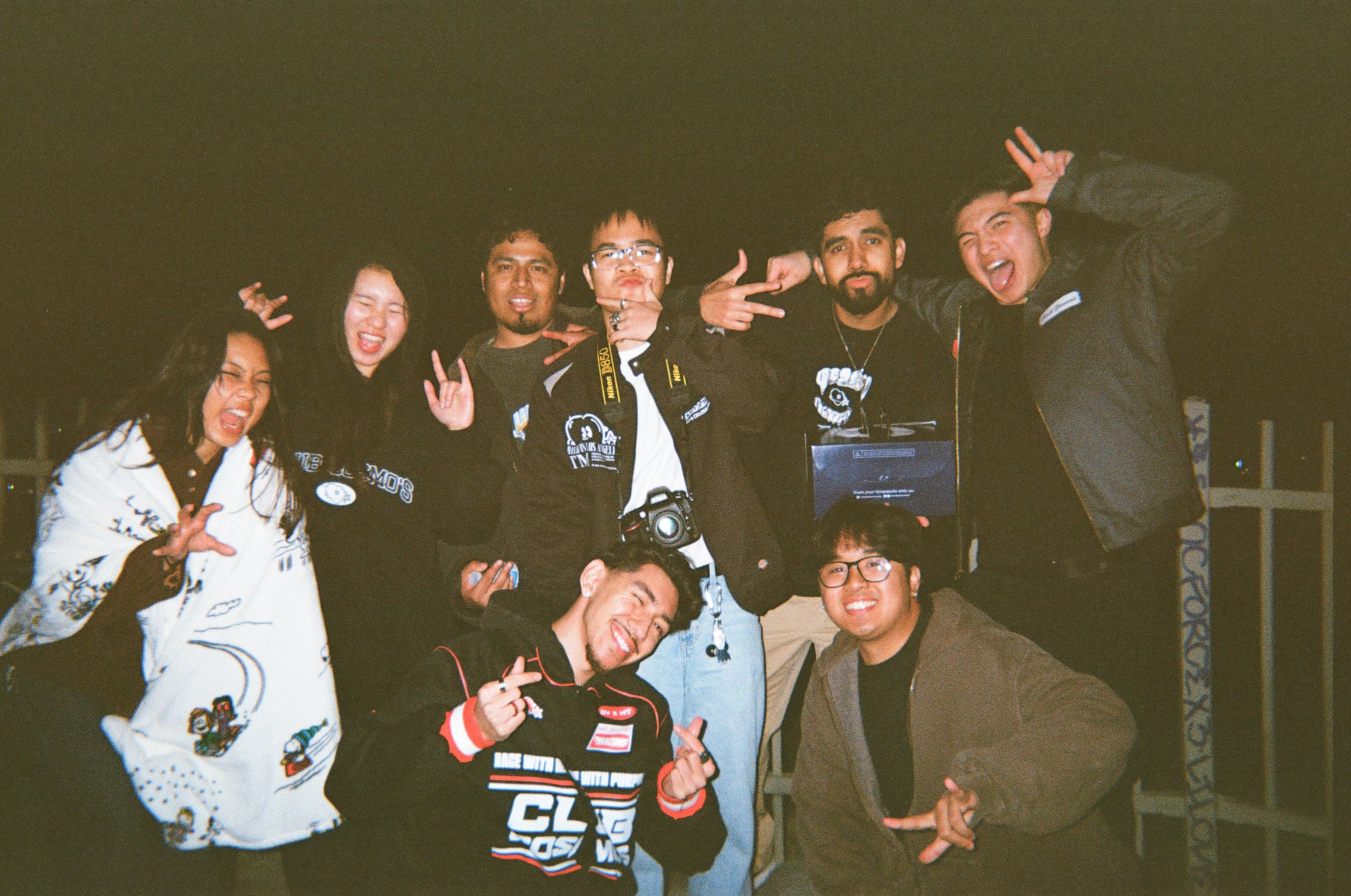 collectives posing together doing funny faces at night with a dark background.
