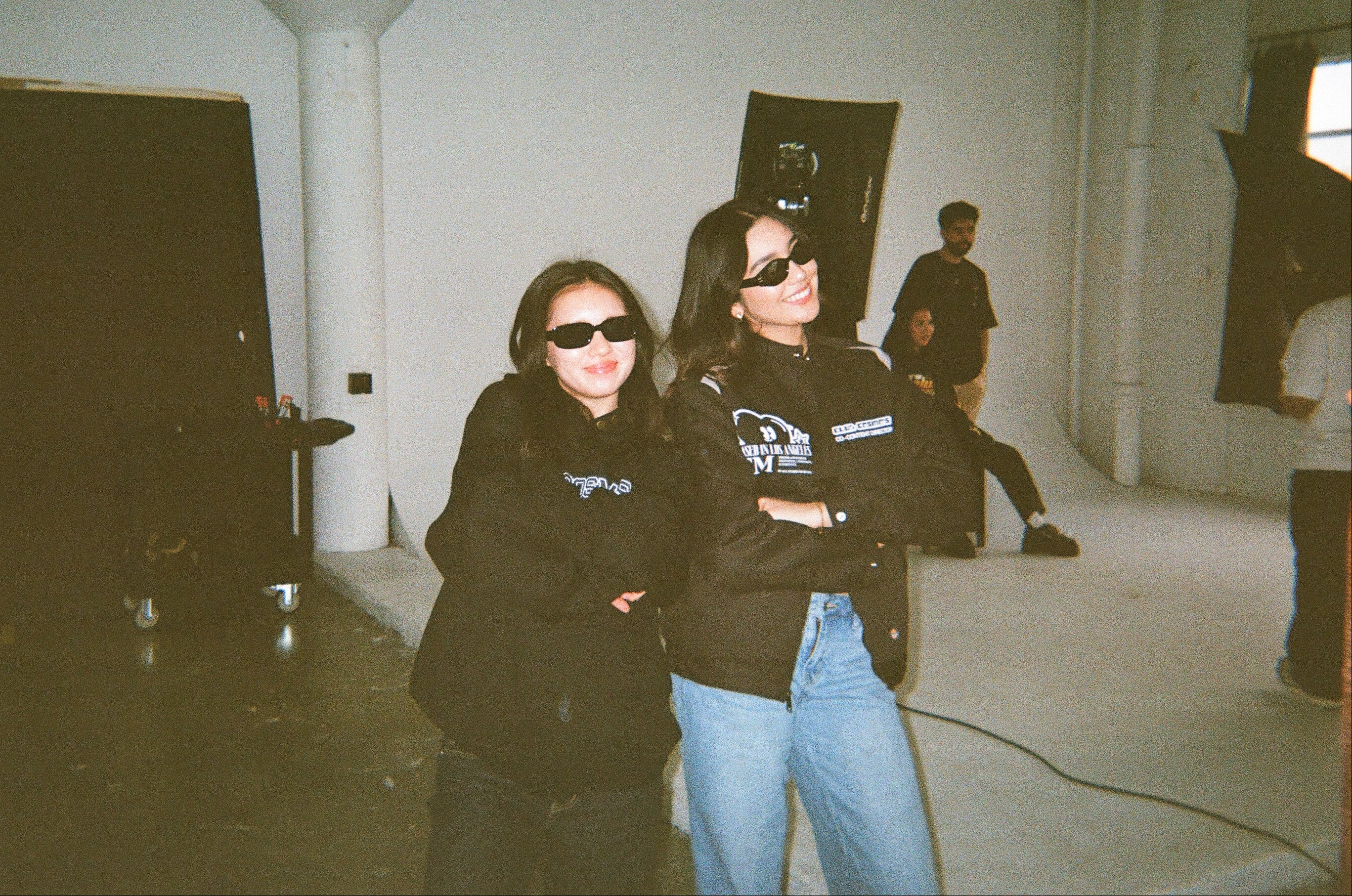 Two Club Cosmo's team members wearing shades smiling standing in a studio room.