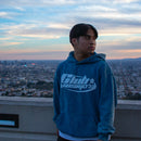 Person wearing a blue hoodie with 'Club Cosmo's' logo against a cityscape background.