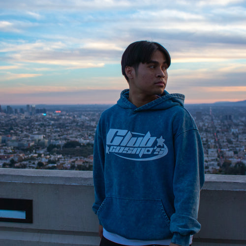 Person wearing a blue hoodie with 'Club Cosmo's' logo against a cityscape background.