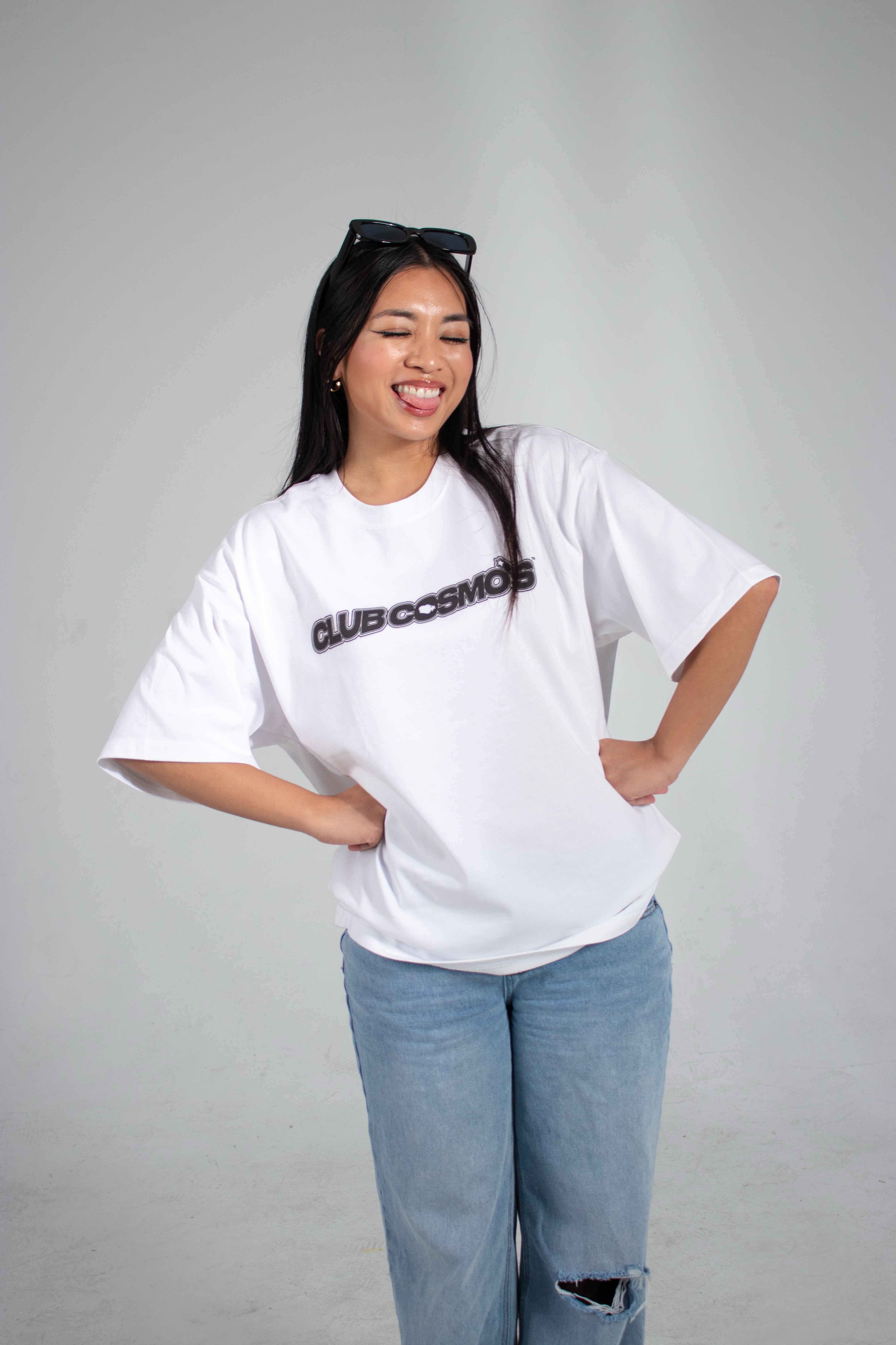 Model wearing a y2k aesthetic white t-shirt with black 'Club Cosmos' text on a white background.